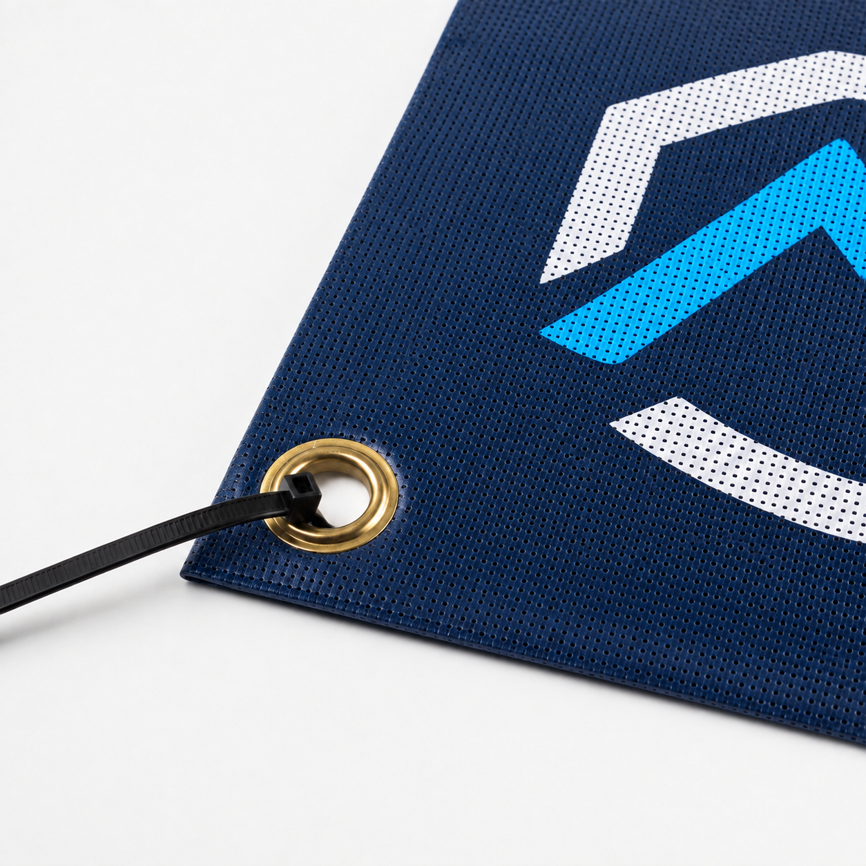 Close-up of perforated custom mesh banner with clean adhesive-bonded hem and brass grommet